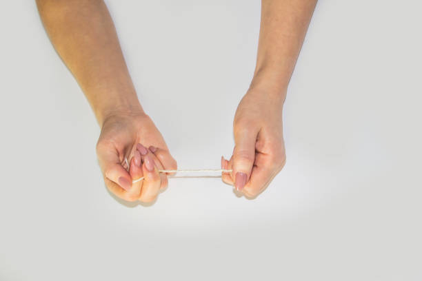 istock Women's hands hold the rope in the light background. Female hands pull the rope between each other. Hands pull the rope. 1198688037