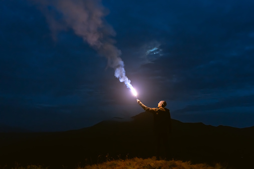 The male with a firework stick standing on a mountain