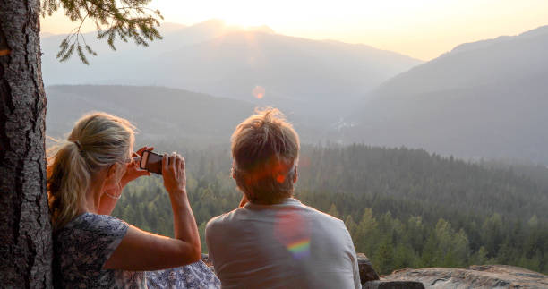 istock Mature couple relax on mountain ledge, look out to view 1198692110
