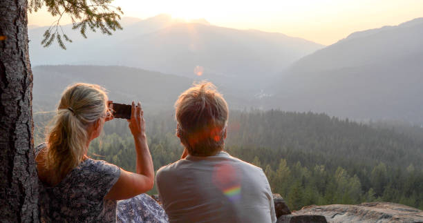 istock Mature couple relax on mountain ledge, look out to view 1198692142