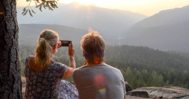 istock Mature couple relax on mountain ledge, look out to view 1198692173