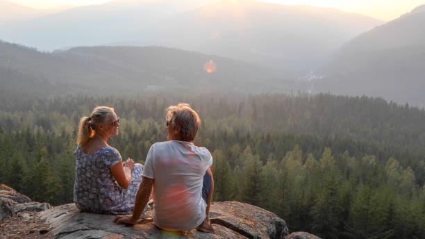 istock Mature couple relax on mountain ledge, look out to view 1198692189