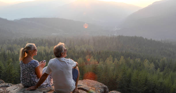 istock Mature couple relax on mountain ledge, look out to view 1198692220