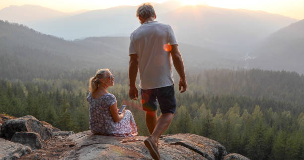 istock Mature couple relax on mountain ledge, look out to view 1198692233