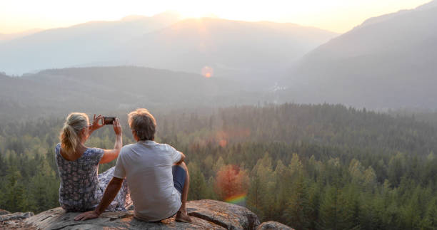istock Mature couple relax on mountain ledge, look out to view 1198692235