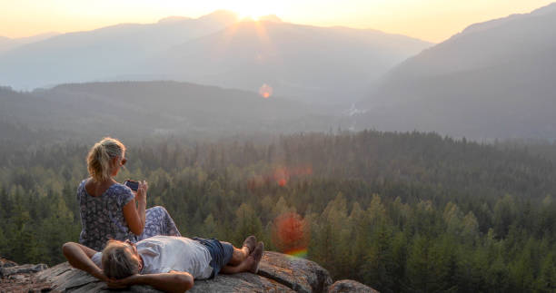 istock Mature couple relax on mountain ledge, look out to view 1198692269