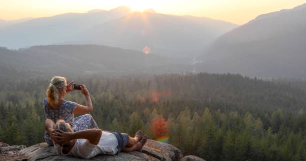 istock Mature couple relax on mountain ledge, look out to view 1198692287