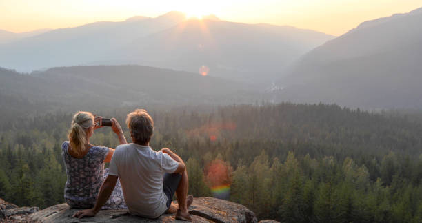 istock Mature couple relax on mountain ledge, look out to view 1198692292