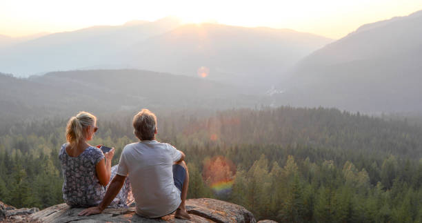 istock Mature couple relax on mountain ledge, look out to view 1198692309