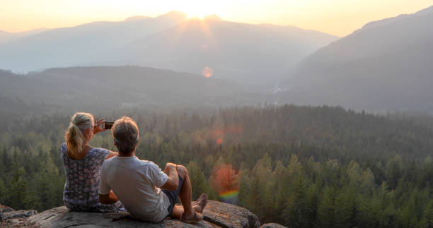istock Mature couple relax on mountain ledge, look out to view 1198692361