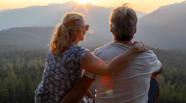 istock Mature couple relax on mountain ledge, look out to view 1198692877