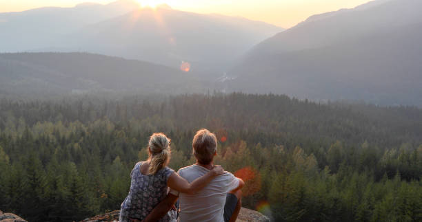 istock Mature couple relax on mountain ledge, look out to view 1198692902