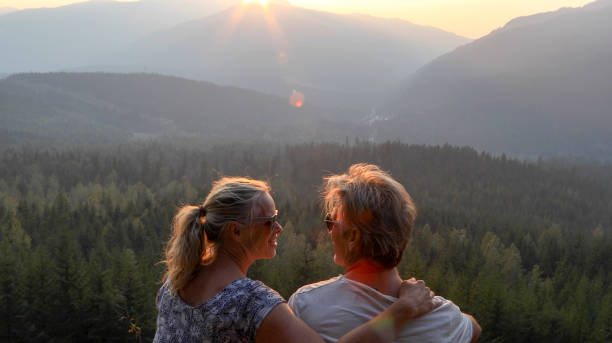 istock Mature couple relax on mountain ledge, look out to view 1198692956