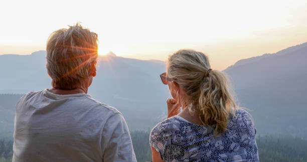 istock Mature couple relax on mountain ledge, look out to view 1198692973