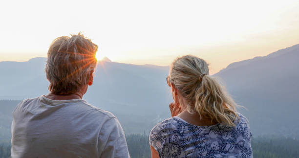 istock Mature couple relax on mountain ledge, look out to view 1198692978