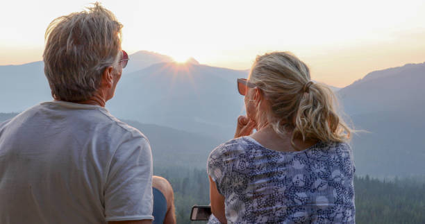 istock Mature couple relax on mountain ledge, look out to view 1198692984