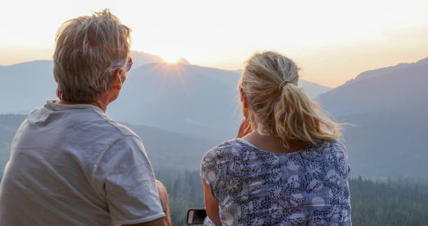 istock Mature couple relax on mountain ledge, look out to view 1198693040