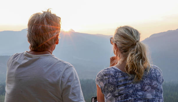 istock Mature couple relax on mountain ledge, look out to view 1198693043