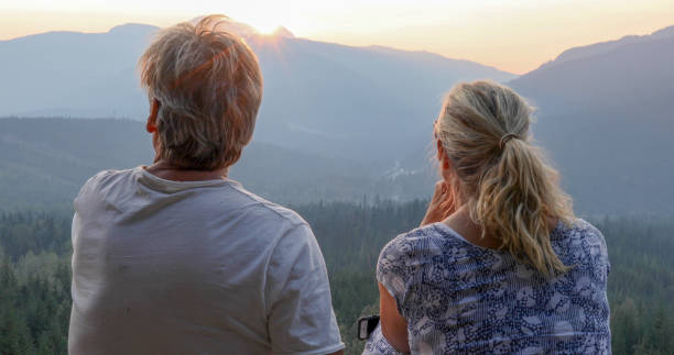 istock Mature couple relax on mountain ledge, look out to view 1198693059