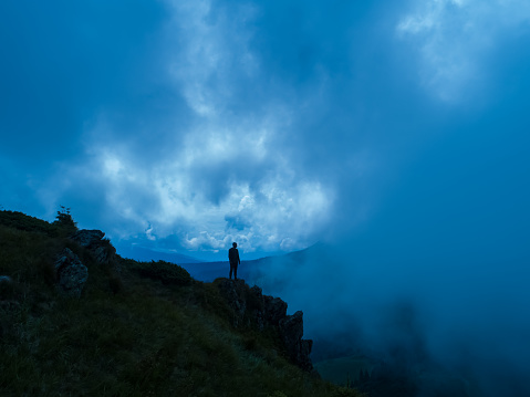 The male standing on the foggy mountain. evening night time