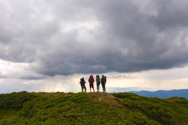 istock The four active people on a mountain against the picturesque cloud view 1198693375