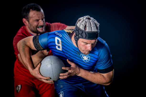 istock Determined rugby player running with the ball while getting tackled from behind 1198693484