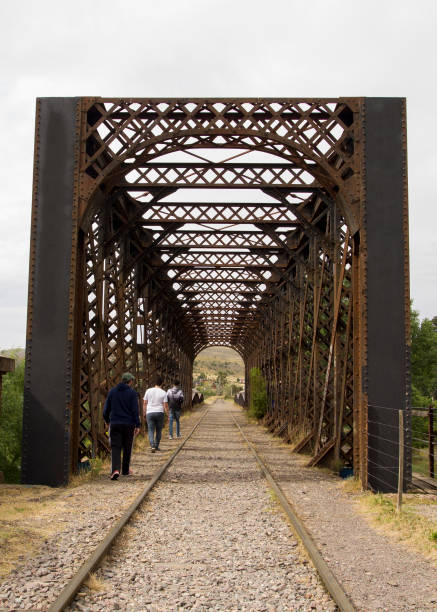 Three tourists walking beside the railway tracks under the bridge. Tandil, Buenos Aires, Argentina.