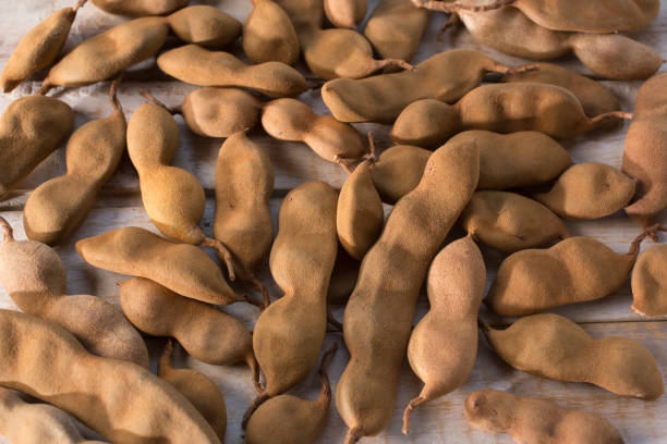Tamarindo fruit heap on white wooden table. Natural day lighting.