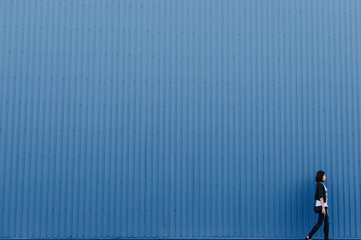 Woman walks near classic blue color wall, copy space background