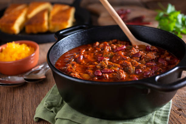 Chile Classic Southwestern Chili in a Cast Iron Dutch Oven with Corn Bread and Cheddar Cheese Homemade Chili stock pictures, royalty-free photos & images