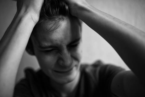 istock Teen guy squeezes his head and screams and grimaces 1198713075