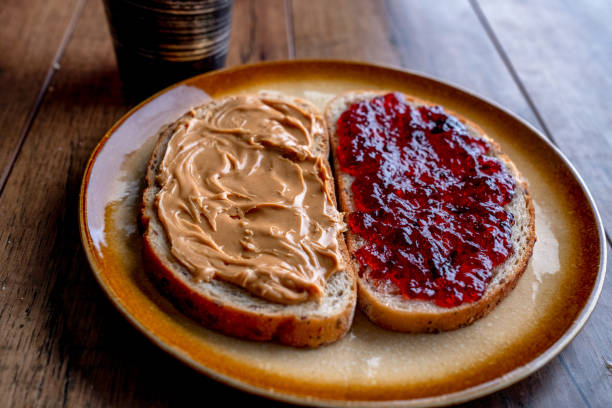 istock Open Face Peanut Butter and Jelly Sandwich on a Rustic Cutting Board on Artisan Multi-Grain Bread 1198713562