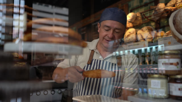 Cheerful waiter grabbing a sweet pastry snack and placing it on plate at a bakery