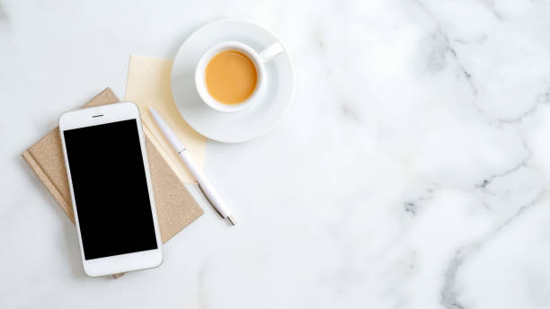 istock Flat lay, top view office table desk. Freelancer workplace with cup of coffee, paper notebook, office supplies and smartphone screen mockup 1198720997