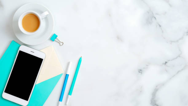 istock Flat lay feminine home office desk with smartphone empty screen mockup, mint notebook, stationery, stylish accessories, coffee cup on marble background. Top view with copy space. 1198721017