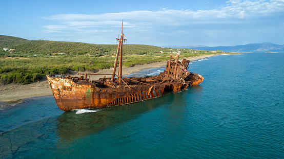 Huge rusty shipwreck stranded on rocks on the long sand beach of south Peloponnese in Greece. Wreck is in very bed condition, exposed to wind and waves.photo taken with drone