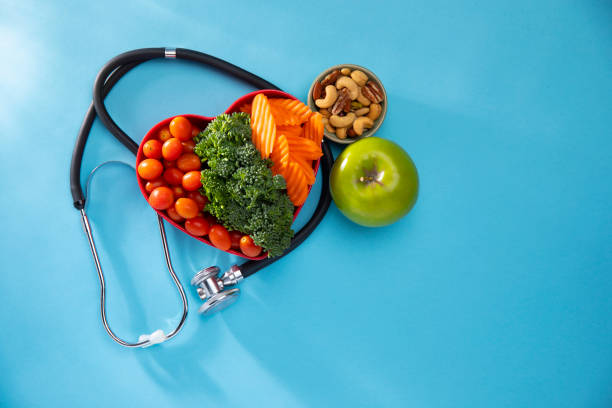 istock Vegetables in a heart bowl surrounded by a stethescope with  blue background 1198722955