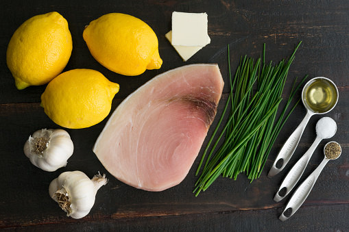 Swordfish steak, lemons, chives, and other ingredients used to make Lemon Garlic Swordfish