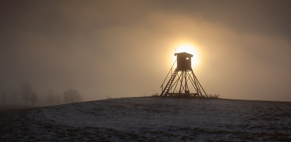 Lookout tower for hunting on the hill at sunrise. Winter scenery.