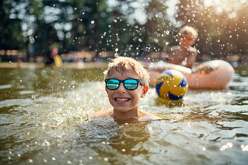 Kids are splashing and having fun on swim ring floating on the lake. Kids are laughing and having fun.\nNikon D810