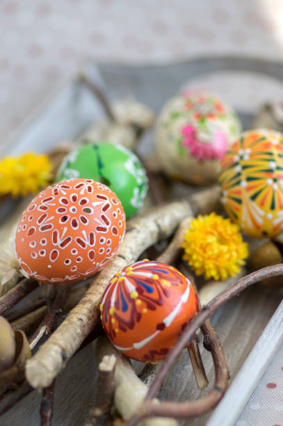 istock Homemade handmade painted Easter eggs on birch branches on grey wooden tray, traditional hnadcraft eggs 1198728513
