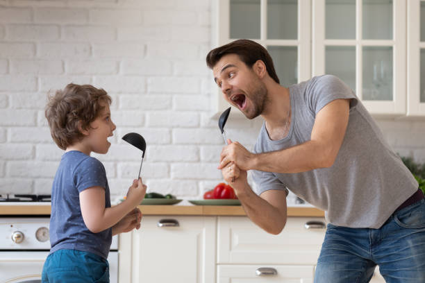istock Father dancing with son holding kitchen spoon like microphone singing 1198734217
