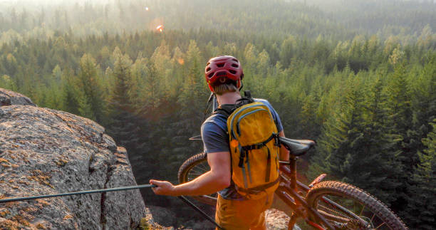 Mountain biker uses rope for ascent, above mountains and valley