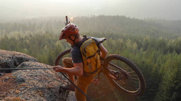 istock Mountain biker uses rope for ascent, above mountains and valley 1198734839
