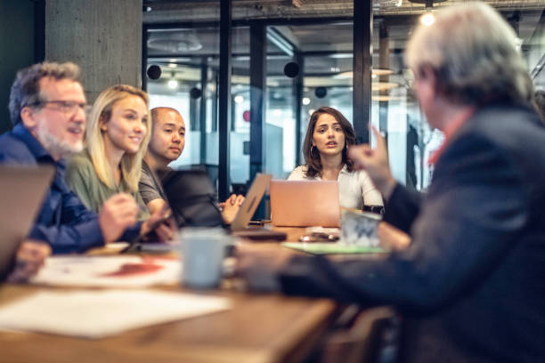 Business discussions at a conference table Multi-ethnic group of business people discussing ideas at a conference table in a modern office. multi generation family stock pictures, royalty-free photos & images