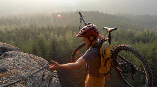 istock Mountain biker uses rope for ascent, above mountains and valley 1198735544