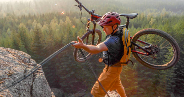 istock Mountain biker uses rope for ascent, above mountains and valley 1198735559
