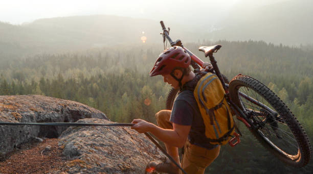 istock Mountain biker uses rope for ascent, above mountains and valley 1198735567