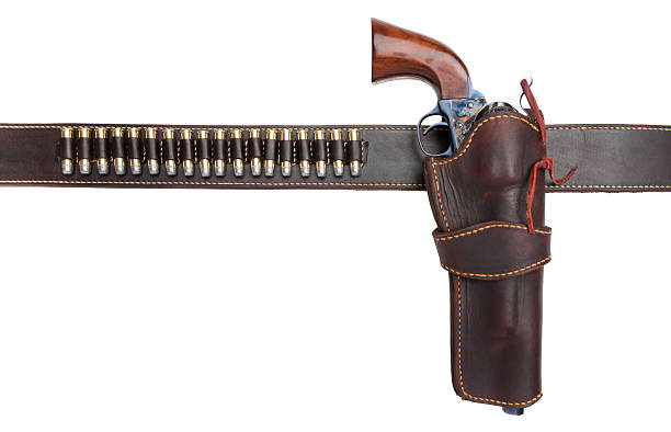 cartridge belt with holster, gun, and ammunition A brown leather belt with a holster for an old fashioned revolver, and loops for bullets. Isolated on a pure white background. No logos, trademarks, brand names or identification numbers visible in this image. ammunition photos stock pictures, royalty-free photos & images