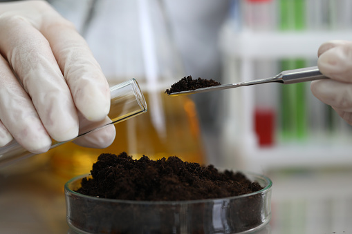 Female chemist in white protective gloves hold test tube against chemistry lab background closeup. Express research crop soil content of beneficial and harmful substances concept